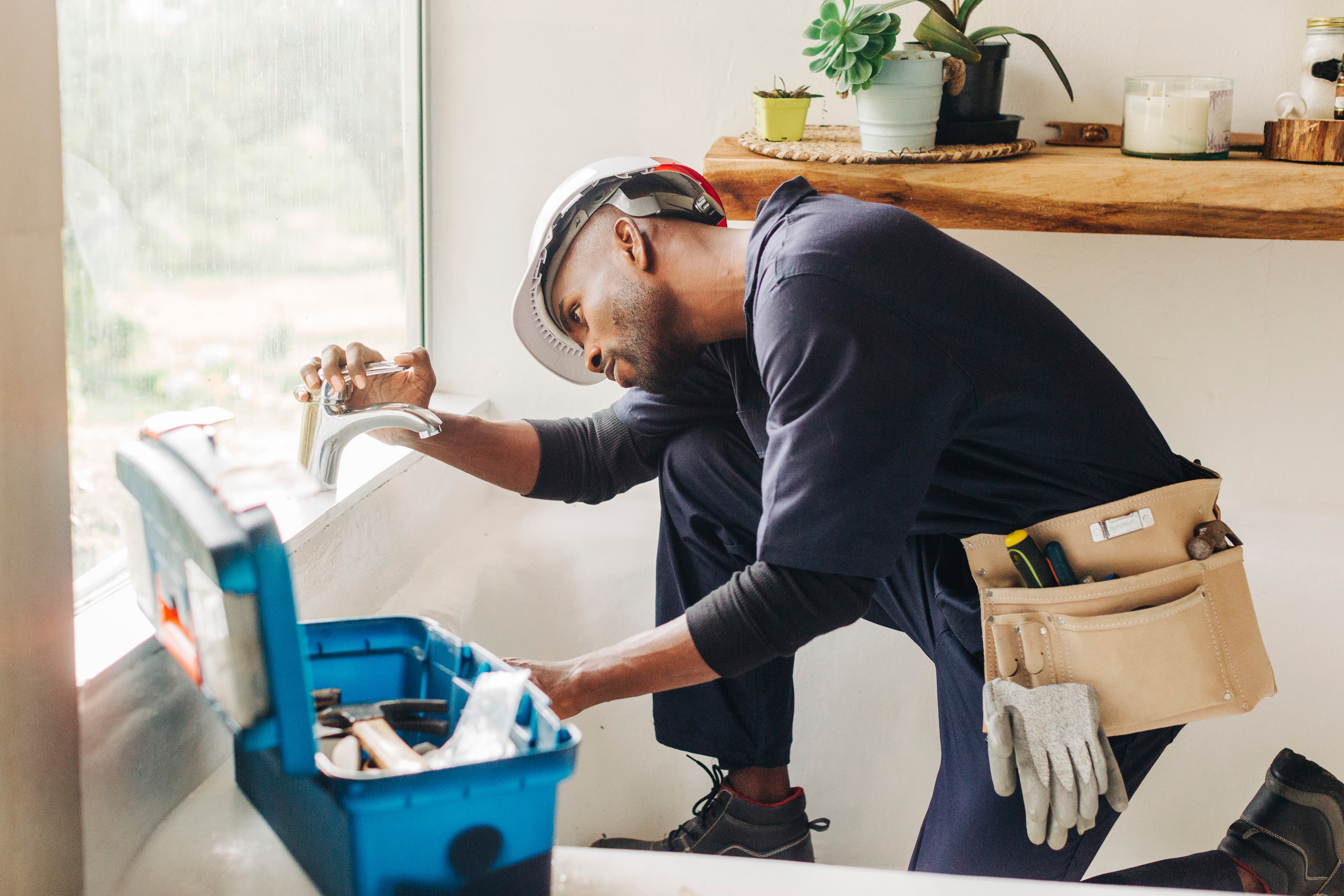 Plumber working on a bath faucet in a home
