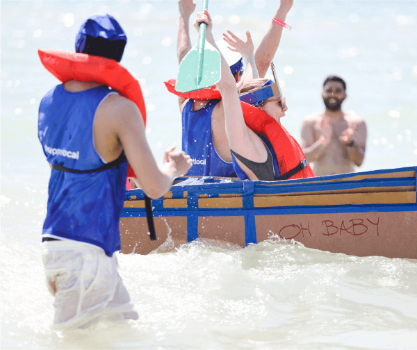 Group of people in the ocean in a cardboard boat celebrating