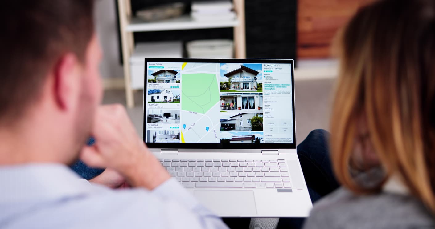 Couple looking away from camera looking at a laptop with home son it