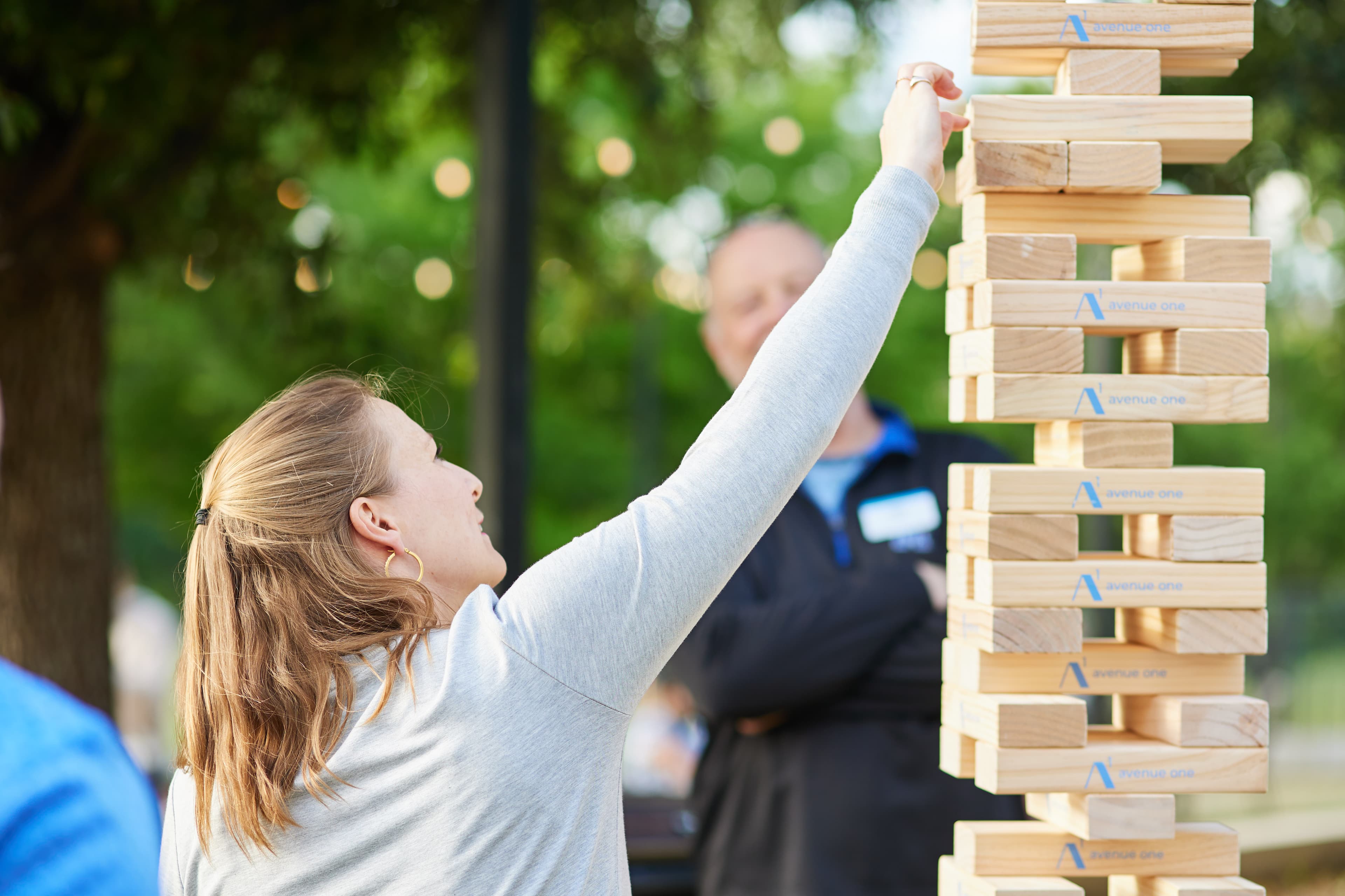 Woman playing giant jenga and reaching for a block